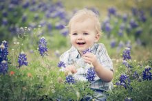 boy sitting in bluebonnets laughing