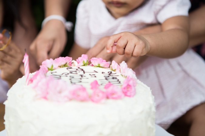 baby girl reaching for her birthday cake